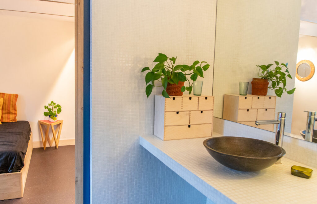 wanden en badkamertablet met glasmozaïek van Impermo en ladekastje in berkenmultiplex van Ikea, blauwe schuifdeur, witte tegels, badkamer, slaapkamer